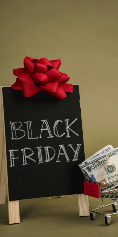 A chalkboard sign with Black Friday written on it and a small shopping cart with dollar bills, ideal for sales promotions.