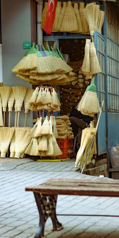 Colorful straw brooms displayed outside a traditional urban shop, Turkey.