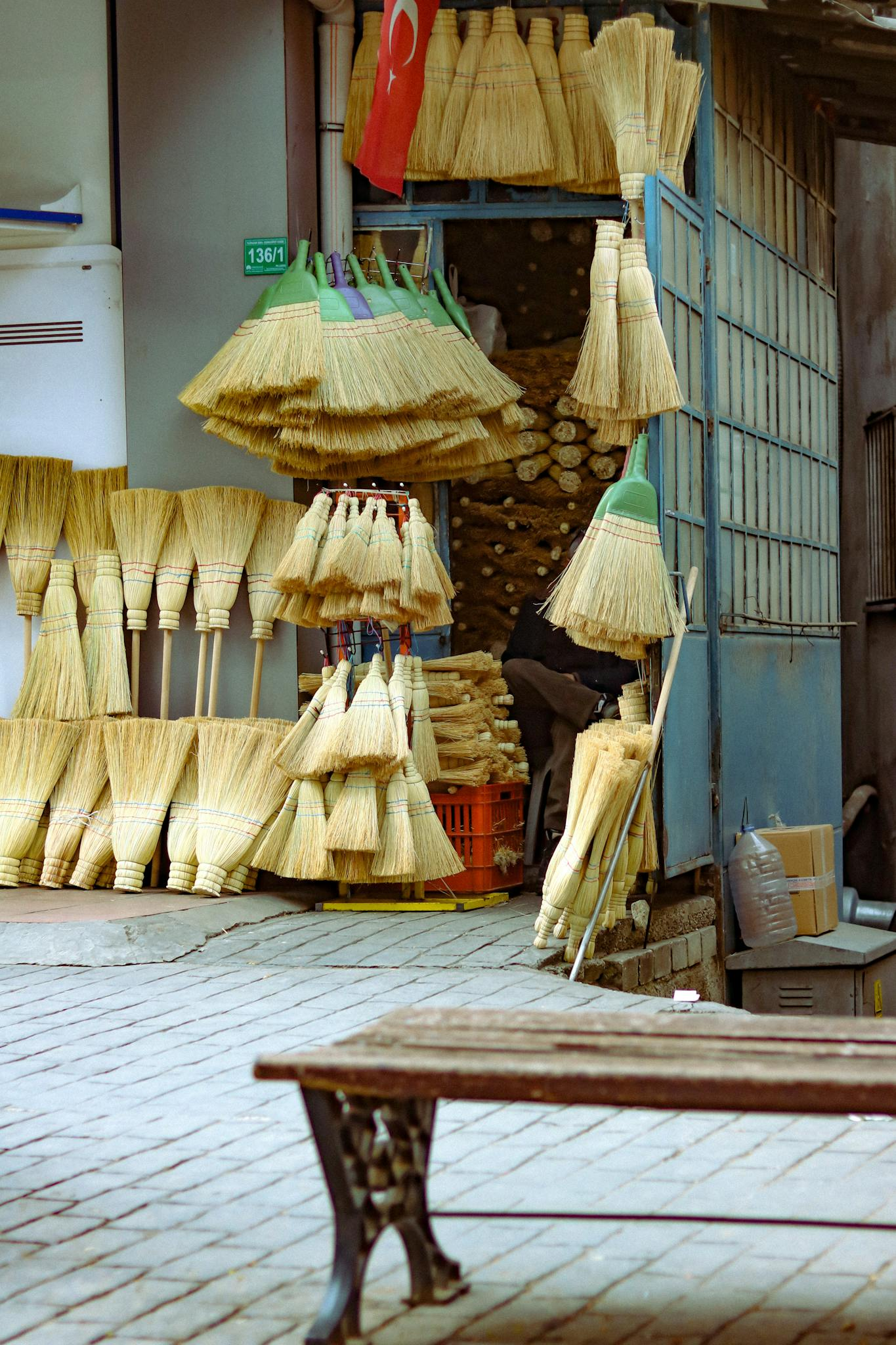 Colorful straw brooms displayed outside a traditional urban shop, Turkey.